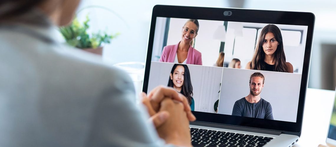 Back view of female employee speaking on video call with diverse colleagues on online briefing with laptop at home.
